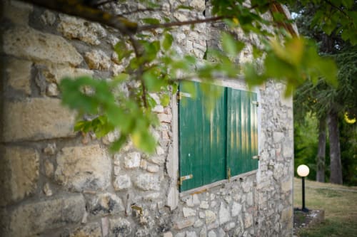 Persiane verdi su edificio in pietra dell'hotel Il Podere Prato a Predappio Alta, Italia