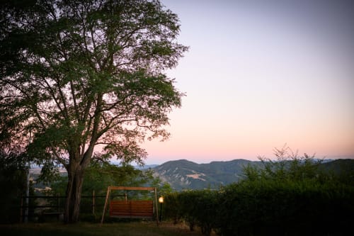 Altalena in legno sotto un antico albero a Il Podere Prato, Predappio Alta, con vista sulle colline toscane al tramonto