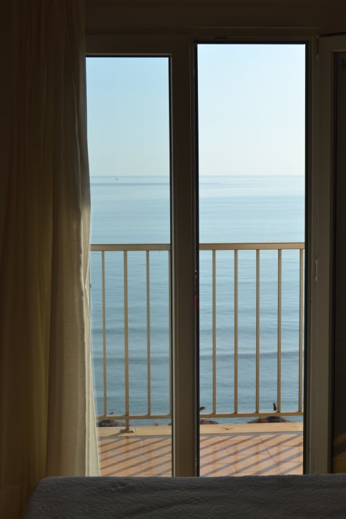 Camera con balcone vista mare all'Hotel Sa Roqueta di Can Picafort, terrazza in legno, porte scorrevoli in vetro e orizzonte oceanico sereno