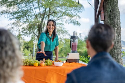 Donna che serve un fresco smoothie al tavolo esterno con frutta a Il Podere Prato, Predappio Alta