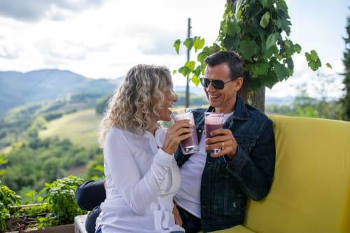 Coppia che degusta cocktail sui sedili gialli con vista sulle dolci colline della Toscana a Il Podere Prato