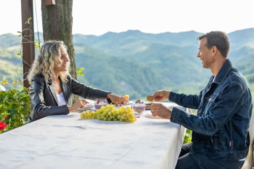 Coppia che cena all'aperto presso Il Podere Prato con lo splendido panorama delle colline toscane e vigneti sullo sfondo