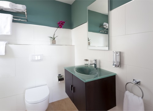 Modern bathroom at Hotel Sa Roqueta with turquoise countertop, dark vanity, white tiles, and green accent wall