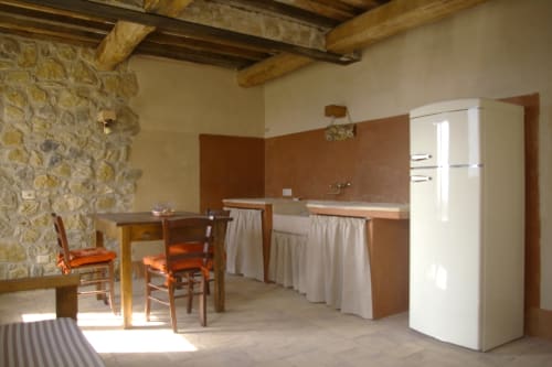 Cucina rustica di Casale di Poggioferro con travi in legno, muri in pietra e arredi vintage