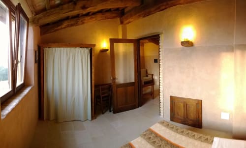 Camera rustica al Casale di Poggioferro B&B con travi a vista, illuminazione calda, porte in legno e arredamento toscano tradizionale