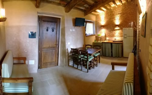 Interno rustico di Casale di Poggioferro con travi a vista, tavolo da pranzo, cucina e illuminazione calda