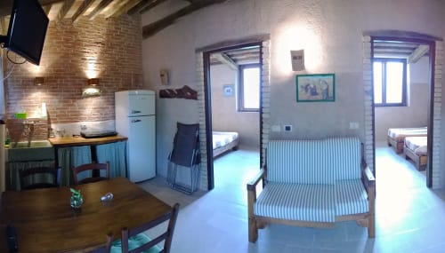 Appartamento Casale di Poggioferro con cucina, zona pranzo, divano a righe e accesso alla camera da letto a Poggioferro