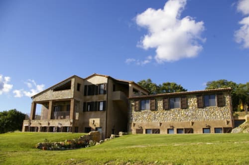 Casale di Poggioferro con facciata in pietra e terrazza panoramica sui prati verdi della Toscana