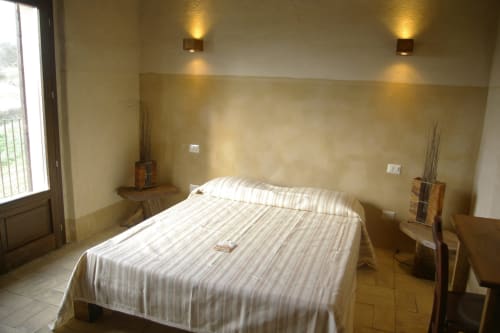 Camera moderna al Casale di Poggioferro B&B in Toscana con biancheria a righe, illuminazione calda e pavimenti in cotto