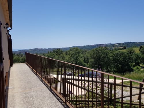Vista sulla campagna toscana dal balcone di Casale di Poggioferro con vallate verdi e chiesa in lontananza