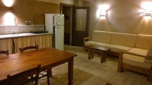 Appartamento Casale di Poggioferro con tavolo da pranzo in legno, divano color panna, angolo cottura e illuminazione calda a Poggioferro, Toscana