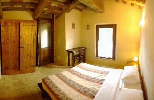 Camera luminosa e gialla presso Casale di Poggioferro B&B con travi in legno, pavimento in cotto e arredamento rustico