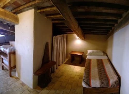 Camera rustica a Casale di Poggioferro con travi a vista, pavimenti in terracotta e arredi in legno tradizionali in Toscana