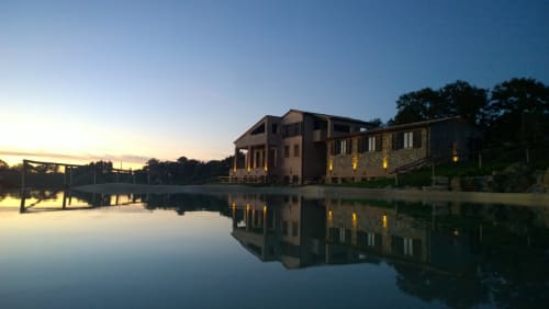Casale di Poggioferro BnB al tramonto, edificio in pietra riflesso nell'acqua calma con finestre illuminate
