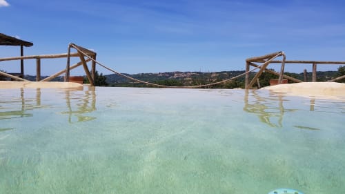 La piscina a sfioro di Casale di Poggioferro con travi in legno affacciata sulle colline toscane
