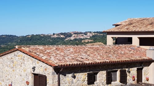 Edifici in pietra con tetto in cotto presso Casale di Poggioferro B&B in Toscana, con colline e cipressi sullo sfondo