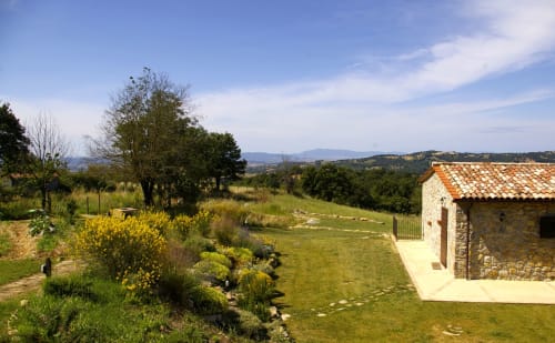 Toscana rurale a Casale di Poggioferro: edificio in pietra, giardino curato e colline ondulate al tramonto
