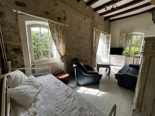 Spacieuse suite chambre aux Fleurs de Cerises avec lit, sièges en cuir noir et vue sur jardin