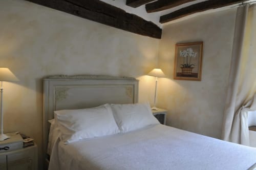 Chambre élégante à Aux Fleurs de Cerises, Le Plessis Luzarches, avec parure blanche, poutres apparentes et éclairage doux