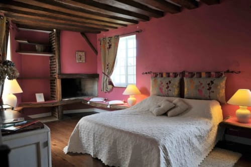 Chambre de charme aux Fleurs de Cerises avec murs rose pâle, poutres apparentes et cheminée rustique au Plessis-Luzarches