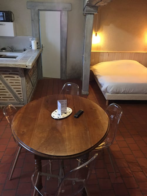 Studio à l'Hôtel De La Bonnheur à Bracieux : table ronde en bois, chaises transparentes, lit, kitchenette, ambiance chaleureuse