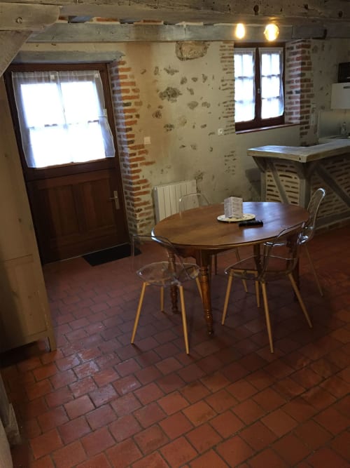 Studio rustique à l'Hôtel De La Bonnheur à Bracieux avec table à manger, murs en brique et poutres apparentes