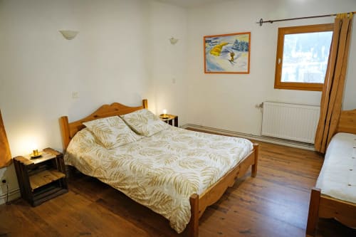 Chambre douillette à la B&B L'étape Du Fanfoué à Chamrousse avec lit en bois, vue montagne et décoration thématique ski