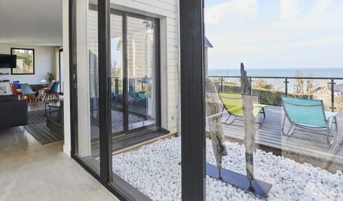 Terrasse élégante avec vue sur la mer et la plage, équipée de fauteuils confortables pour profiter d'un moment de détente.