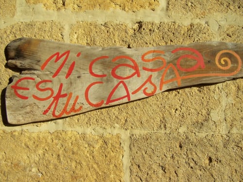 Cartello in legno con testo rosso recante 'Mi casa es su casa' presso l'Agri-Bio Santa Palmira a Pomarance