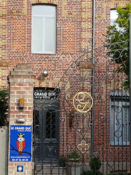 Entrée du Gîte Le Grand Duc à Valenciennes avec portail noir ouvragé et façade en brique