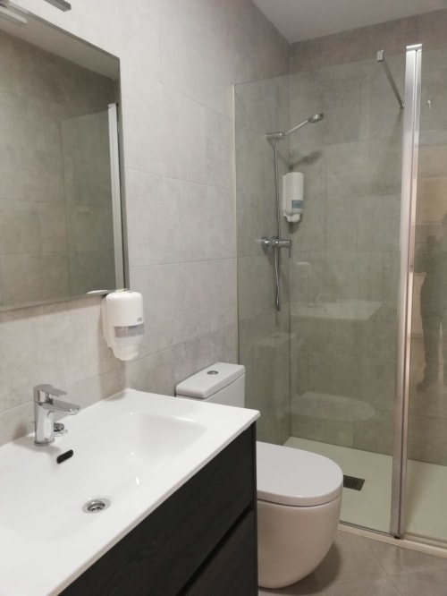 Baño moderno con lavamanos blanco, inodoro y cabina de ducha de cristal en el apartamento El Faro De Los Genoveses en San José,