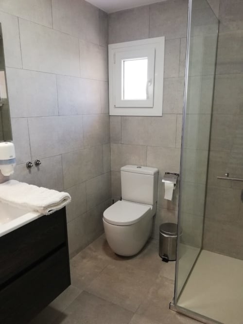 Baño moderno en el apartamento El Faro De Los Genoveses con inodoro blanco, paredes de azulejos, cabina de ducha y lavamanos