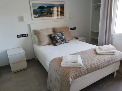 Dormitorio moderno en El Faro De Los Genoveses con obra de arte con vistas al mar, cama blanca y decoración costera en San José, Almería