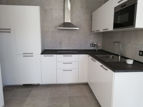 Cocina moderna blanca con encimeras negras y electrodomésticos de acero inoxidable en El Faro De Los Genoveses, San José