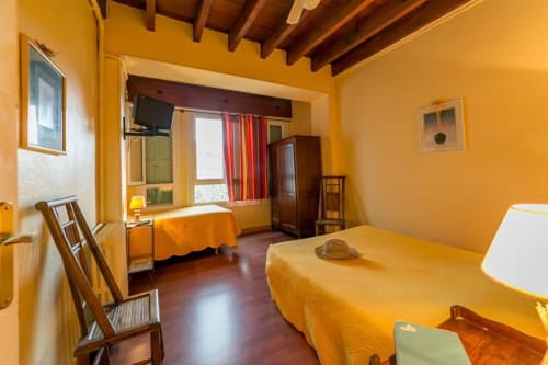 Chambre jaune éclatante aux Chambres D'hôtes Les2lions à Vernet-les-Bains avec deux lits et poutres en bois