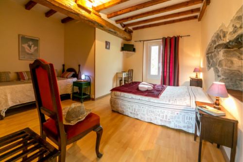 Chambre rustique aux Chambres D'hôtes Les2lions à Vernet-les-Bains avec poutres apparentes, chaise rouge et vue sur les montagnes