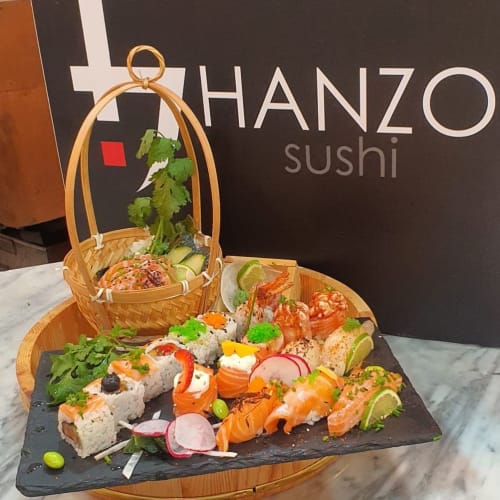 Hanzo Sushi restaurant display with artfully arranged sushi rolls, fresh garnishes, and bamboo basket at Charm Discovery