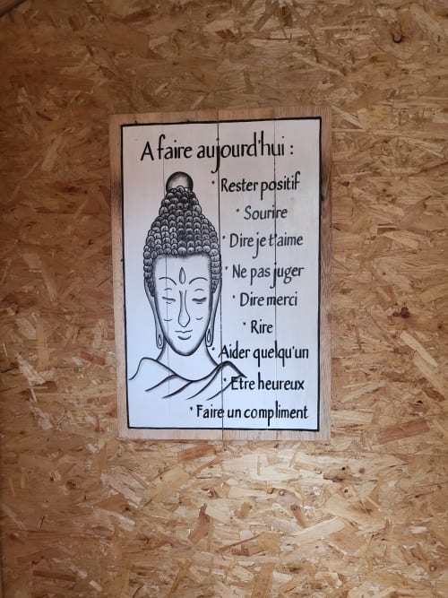 Wooden sign with Buddha head and French wellness tips at Les Refuges Du Chalet in Jalhay