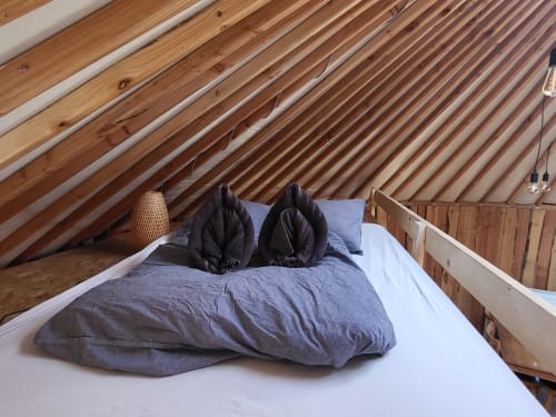 Cozy bed with black pillows in La Yourte de Bouddha cottage at Les Refuges Du Chalet, Jalhay