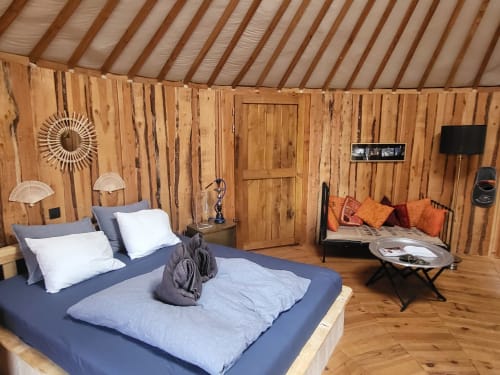 Cozy yurt bedroom at Les Refuges Du Chalet in Jalhay with wooden interior, blue bed, and orange accents