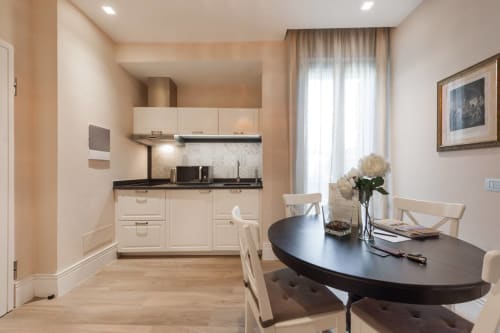 Cucina e sala da pranzo moderna in appartamento a Firenze con tavolo nero, mobili crema e vista sulla città attraverso tende
