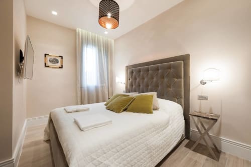 Camera da letto moderna a Firenze con letto queen, testata grigia, cuscini gialli e vista sulla città