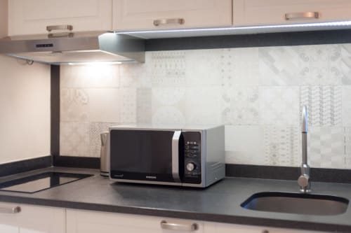 Cucina moderna con microonde Samsung, piano di lavoro nero e piastrelle decorate a Firenze