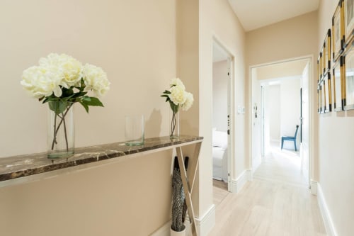Elegante corridoio di appartamento fiorentino con fiori bianchi, bancone in marmo e pavimento in legno chiaro