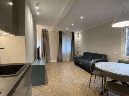 Modern open-plan apartment at Covo del Pirata, Venice, with kitchen, dining area, black sofa and floor-to-ceiling windows