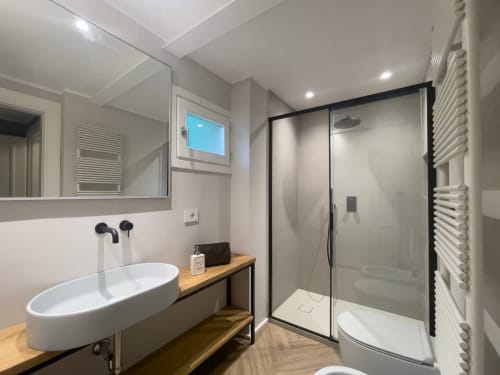Modern bathroom in Apartment Edward at Covo del Pirata, Venice, featuring oval sink, shower enclosure, heated towel rack