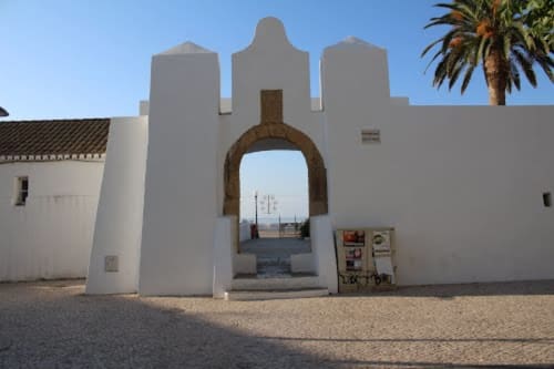 Portão de entrada branco estilo mouro das Residências Armação Beach em Armação de Pêra, Portugal, com palmeira