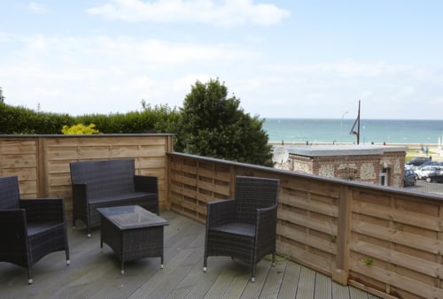 Terrasse privée du Gîte Gabrielle, équipée de mobilier de jardin et offrant une vue partielle sur la mer.