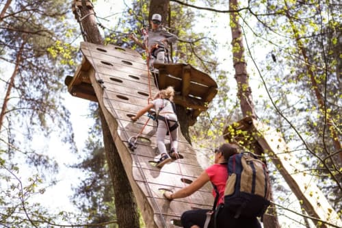 Guests climbing wooden wall at Le Pavillon M adventure park in Grignan