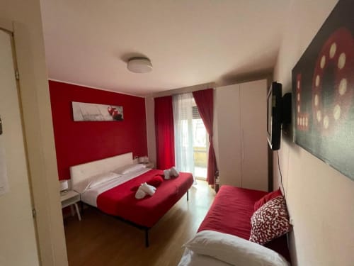Camera rossa presso l'AD Trastevere Guest House a Roma con letti gemelli, accenti rossi e accesso a balcone con vista sulla città